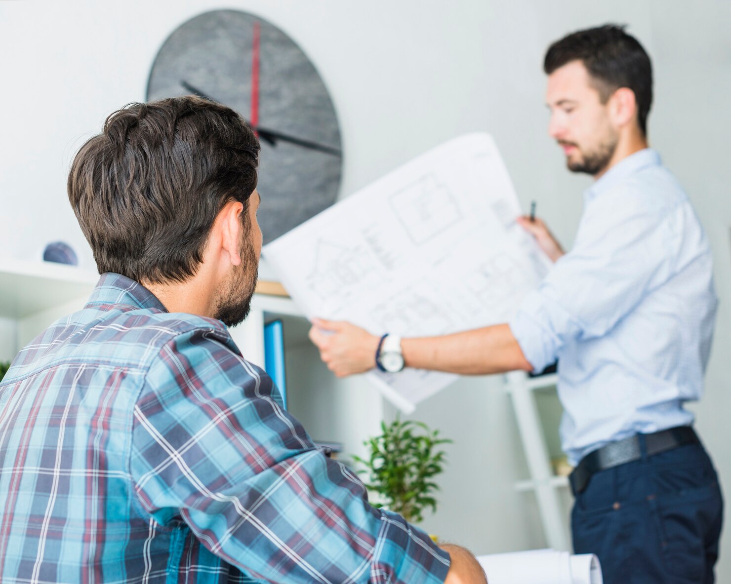 arquitecto que mira su colega que sostiene modelo 23 2147839900